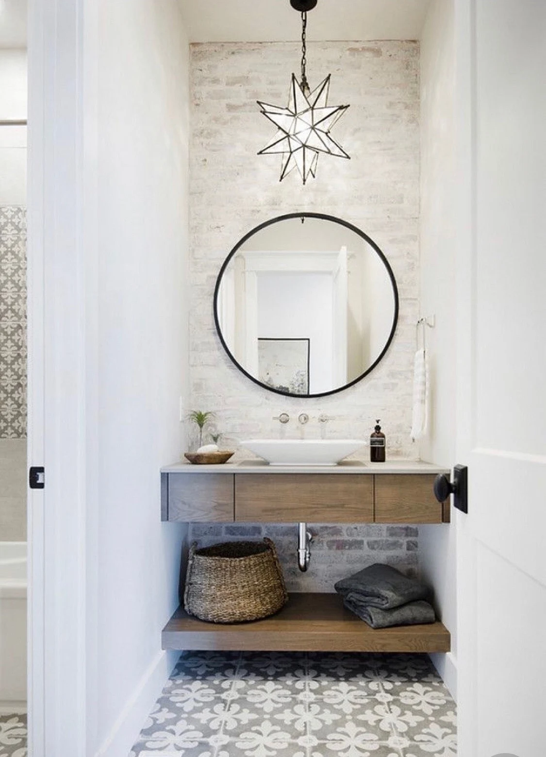 Bathroom with a circular mirror, open wood vanity, and decorative pendant light