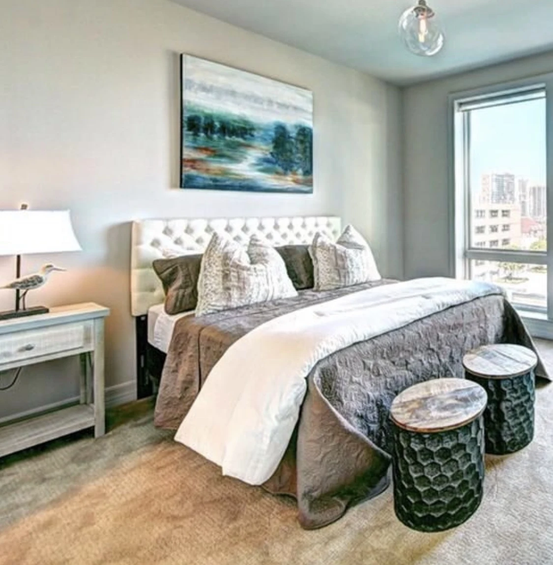 Bedroom with layered neutral bedding, blue walls, and a coastal painting