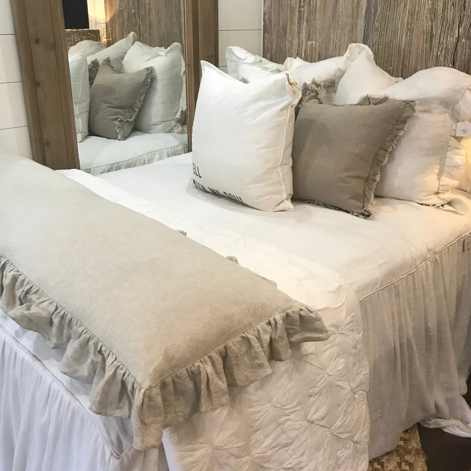 Neutral bedroom with layered cream cushions and a soft fringed coverlet