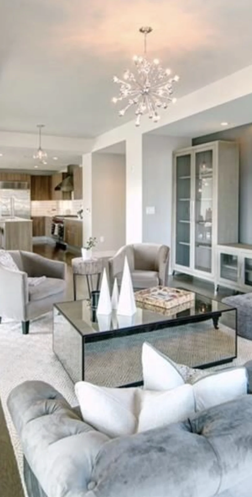 Soft blue living room with upholstered seating, glass coffee table, and built-in cabinetry